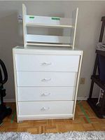 White 4-drawer tallboy dresser with curved handles, visible crack on upper right side