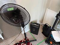 Honeywell heater, Gravity standing fan, and paper shredder together in a room corner