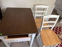 Wood top table with drawer open, two kitchen chairs visible nearby