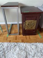 Photo of two side tables: one metal base with wood top, one wood cabinet with metal plate door.