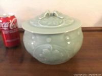 Photo of Asian covered ceramic pot or bowl placed on a wooden surface next to a Coca-Cola can for size reference