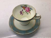 Photo showing top and inside of the Aynsley cup with floral design and the saucer with blue and gold border