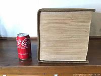 Side view of the Century Dictionary showing the thickness of the book next to a soda can for scale.