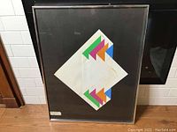 Full front view of framed geometric collage against tiled background