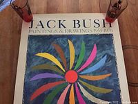 Full view of poster showing title, central abstract motif, two glasses at top corners for scale