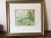 Full front view of framed aquatint depicting windmills by a riverside, with a beige mat and green-gold frame.