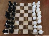 Full view of the chessboard with arranged black and white stone chess pieces.