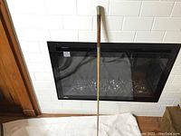 Full length of the vintage whip shown upright against a white backdrop in front of a black decorative fireplace, displaying the whip's entire length and condition.