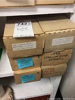 Photo displaying six cardboard boxes labeled with years and brands: 1991 Upper Deck Baseball, 1992 Upper Deck Football, 1993 Stadium Club Baseball, 1992 Topps Gold, 1991 Panini Football, placed on shelf.