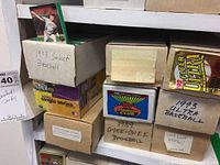 Photo showing labeled cardboard boxes with various baseball card brands including 1993 Select, 1993 Ultra, 1991 Fleer Ultra, 1989 O-Pee-Chee, and 1991 Topps Stadium Club.