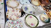 Various decorative china plates with floral patterns and a matching tea pot.