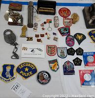 Overview of collectible pins, patches, harmonica, keychains, and other memorabilia displayed on white surface