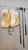 Photo of fox fur mittens, two golf clubs and a riding crop lying on the floor.