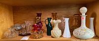 Shelf of 15 assorted glassware vases including colors red, amber, green, white and clear glass