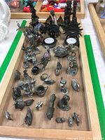 Top view showing an assortment of detailed pewter and brass miniatures including dragons, fairies, and animals on a wooden tray.