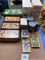 Overview of the lot showing all sports card boxes, loose cards, and collectible cans on the floor with blue tape.