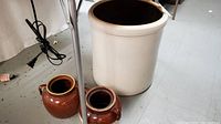 Photo showing the large white stoneware crock and two smaller brownware bean pots without lids on the floor.