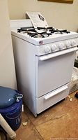 Front view of white gas range showing four burners, control knobs and storage drawer