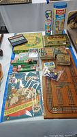 Overview photo of boxed games, toy projector films, cribbage board, wooden blocks, playing cards, and comic cut-outs.