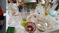 Overview of vintage glassware and collectibles on table including crystal jar, Pepsi glasses, and decorative dishes.