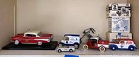 Vintage model cars on display shelf showing small scale cars and trucks, with some boxed USPS limited edition trucks.