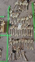 Multiple rows of silver-plated spoons laid out on carpet with a lot tag in the center. The spoons show tarnishing and require cleaning.