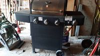 Full front view of the BBQ grill showing three control knobs, lid handle, side burner, and wheeled legs.