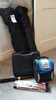 Two portable chairs in black carrying bags, hard black case stove, BBQ set box, and blue and black Thermos lunch bag on floor