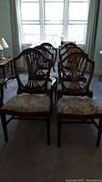 Front view showing all six dining chairs with carved wood backs and floral padded seats.
