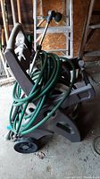 Full view of plastic gray hose reel cart with green hoses and sprinkler heads attached.