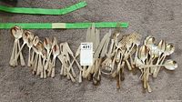 Full set of mixed silverware types laid out on carpet, showing all utensils in the set including spoons, forks, and knives with tag number 431.