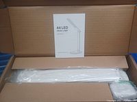 Photo of the 44 LED Desk Lamp still in original packaging with instruction manual visible.