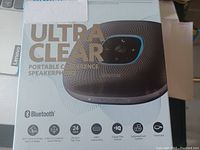 Top view of the boxed Anker Ultra Clear portable conference speakerphone showing product name, key features including Bluetooth, 5m voice coverage, 6 microphones, 24 hours talk time, USB-C connectivity, IQ technology, lightweight and compact design, and travel case included.