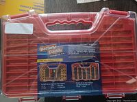 Red plastic battery organizer case with a clear lid, showing compartments for multiple battery sizes and featuring a label describing the battery quality checker functionality.