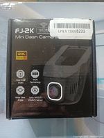 Front view of the FJ-2K WiFi Mini Dash Camera packaging showing the product name and key features such as 2K Ultra HD, real-time video, WDR technology, wide view angle, and Sony IMX335 STARVIS sensor.