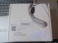 Boxed intelligent neck massager device on a laptop keyboard