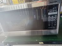 Front view of Panasonic stainless steel microwave with closed door showing digital control panel.