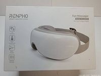 Photo of Renpho eye massager product box with image of the device and feature icons for air pressure, heat compression, music therapy, and vibration massage.