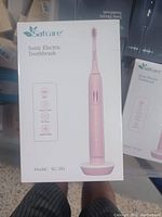 Photo of boxed Safcare Sonic Electric Toothbrush model SC-201 in pink, showing front of box with product image and key features.