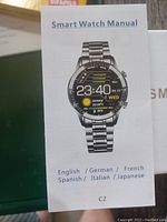 Photo showing smart watch manual with watch face image and languages available.