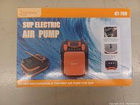 Photo of the product box front for the Stenmay HT-790 SUP Electric Air Pump. Shows branding, product name, image of the pump, and key features like DC powered, rechargeable two-way air pump.