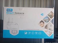 Front view of the retail box showing WiFi Smart Camera branding, image of the camera, and badge icons describing features.