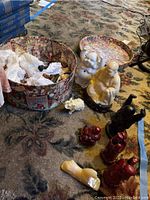 Photo showing open round box containing several small Buddha and animal figurines in ivory and resin colors, placed on patterned carpet.