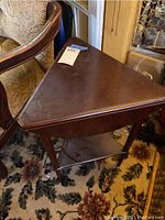 Triangular wooden corner table with drop leaf sides, showing scratches and used condition.