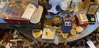 Overhead view of glass table showing jewelry case, trinket boxes, pins and assorted pieces