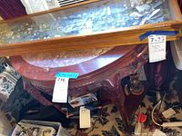 Top view showing crescent-shaped wooden table with glass display case on top (contents not included). The table wood has scratches and wear marks.
