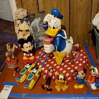 Wide view showing multiple Disney character figurines including Donald Duck, Mickey Mouse, Jiminy Cricket, Pluto, Minnie Mouse, and others, plus two Fantasia VHS tapes.