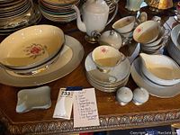 Overview of incomplete Flintridge China serving and tea set on table showing floral design and gold trim.