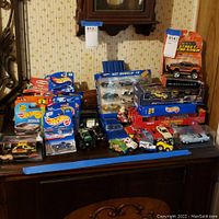 Full view of the lot showing multiple Hot Wheels and Matchbox vehicles including boxed collections and loose cars arranged on a wooden surface
