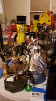 Image of multiple collectible figures including Mr. Peanut, Star Wars C-3PO, and other pop culture figurines grouped together on a surface.